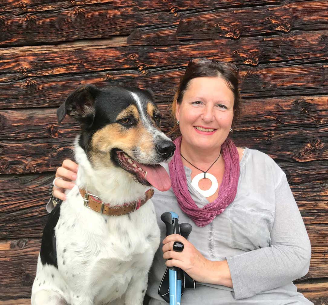 Frau Schenk sitzt neben ihrem Hund Hermine auf einer Bank